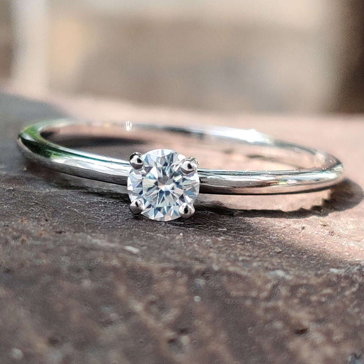 Minimalist round moissanite engagement ring in white gold.
