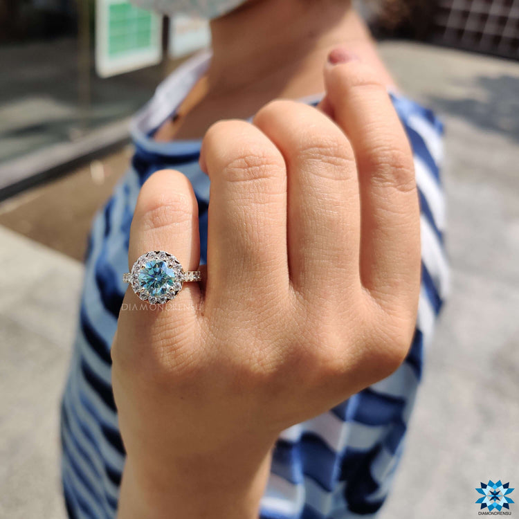 Cyan blue moissanite ring with halo setting.
