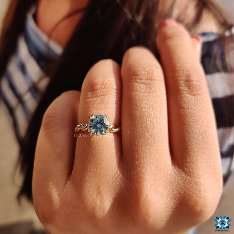 Yellow gold ring with hidden halo and round cut blue moissanite.
