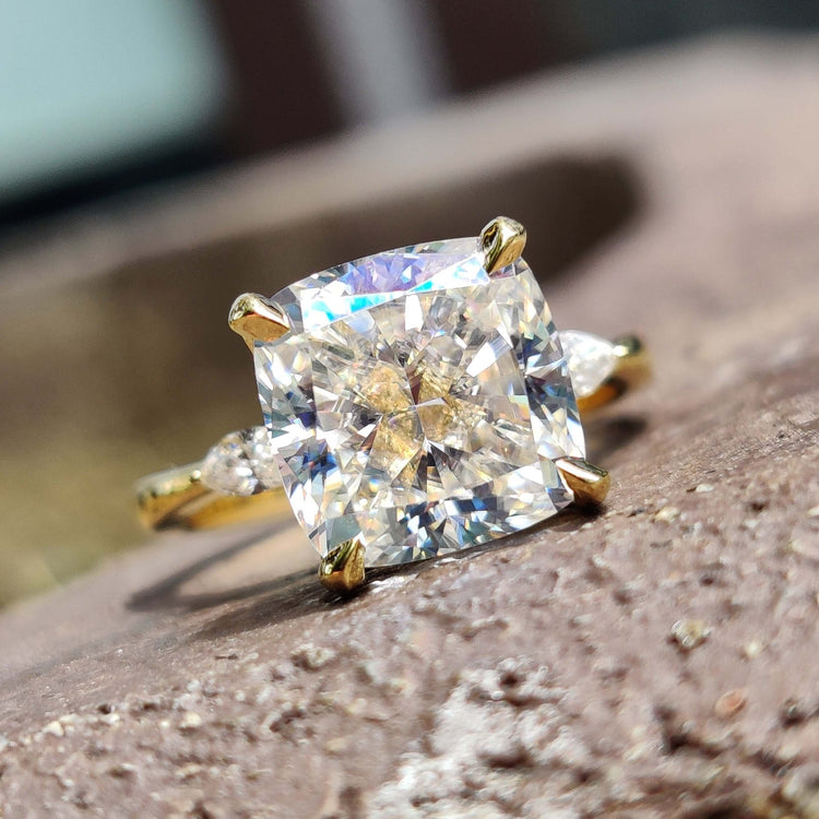 Moissanite three stone engagement ring with cushion cut centre and two pear side stones.
