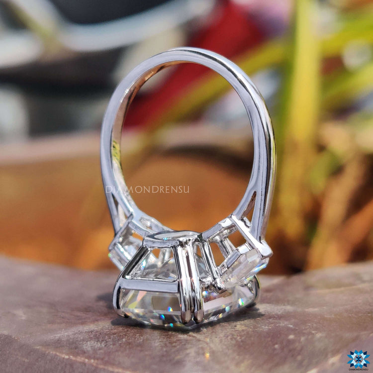 Radiant moissanite ring with side stones and prong setting.
