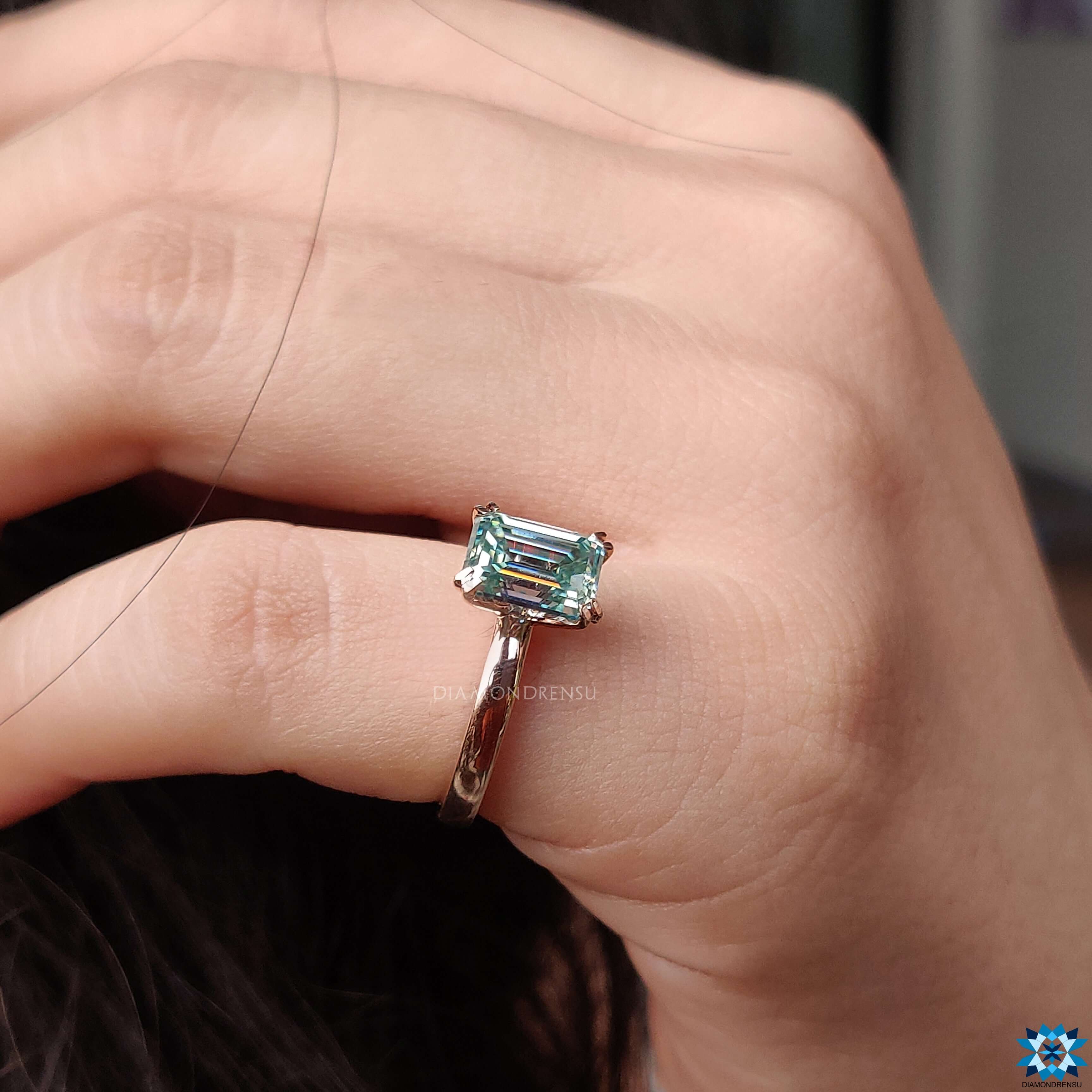 Double claw prong setting holding a stunning emerald cut moissanite ring.