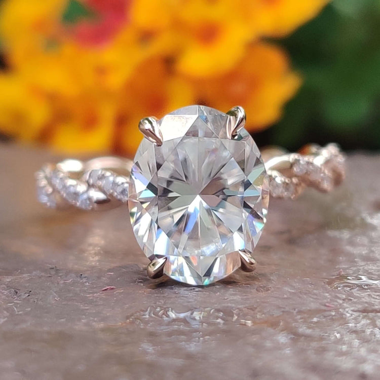 Oval cut moissanite engagement ring in rose gold with twisted band.
