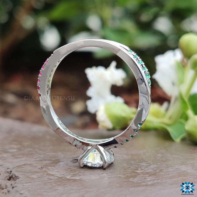 Round cut center stone with colorful ruby and emerald side accents.
