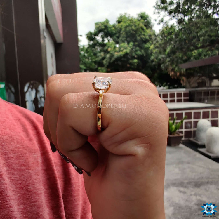 Moissanite engagement ring in yellow gold with 4 prong cushion stone.
