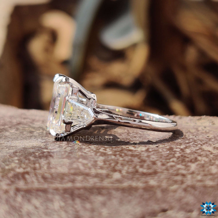Handmade white gold engagement ring with emerald moissanite and bullet sides.
