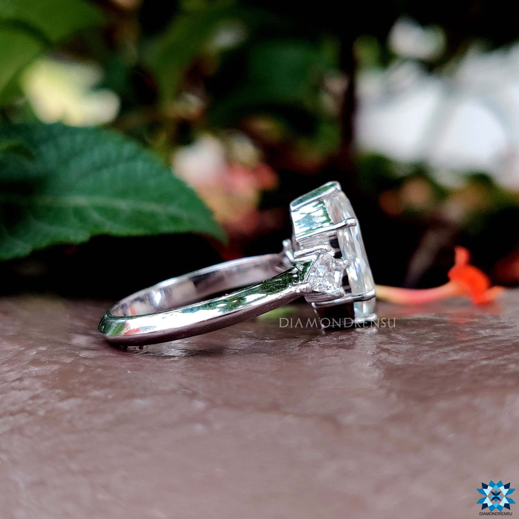 Custom engagement ring with v shaped prong and kite cut side stones in white gold.
