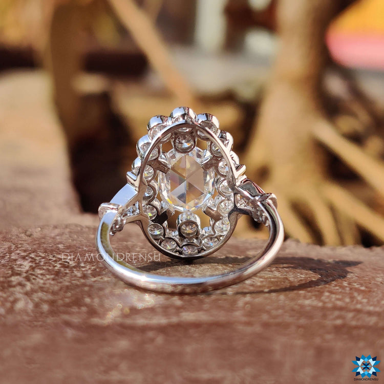Round cut halo setting with rose cut oval moissanite in white gold.
