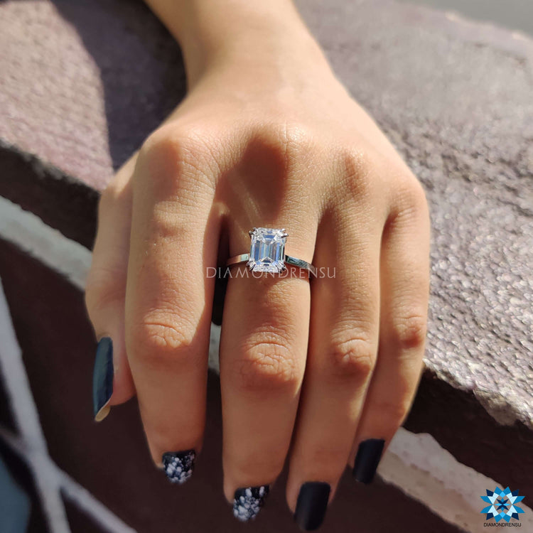 White gold solitaire ring with emerald moissanite center.
