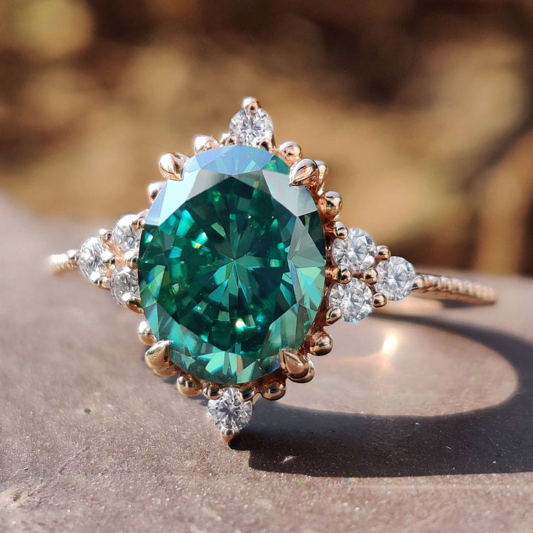 Oval cut engagement ring with green moissanite center stone.
