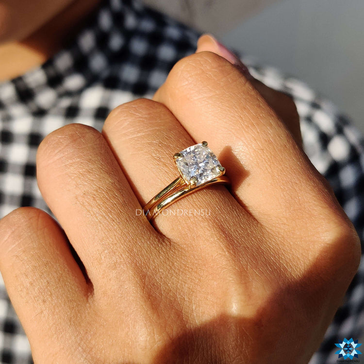 Yellow gold cathedral setting ring with cushion moissanite.
