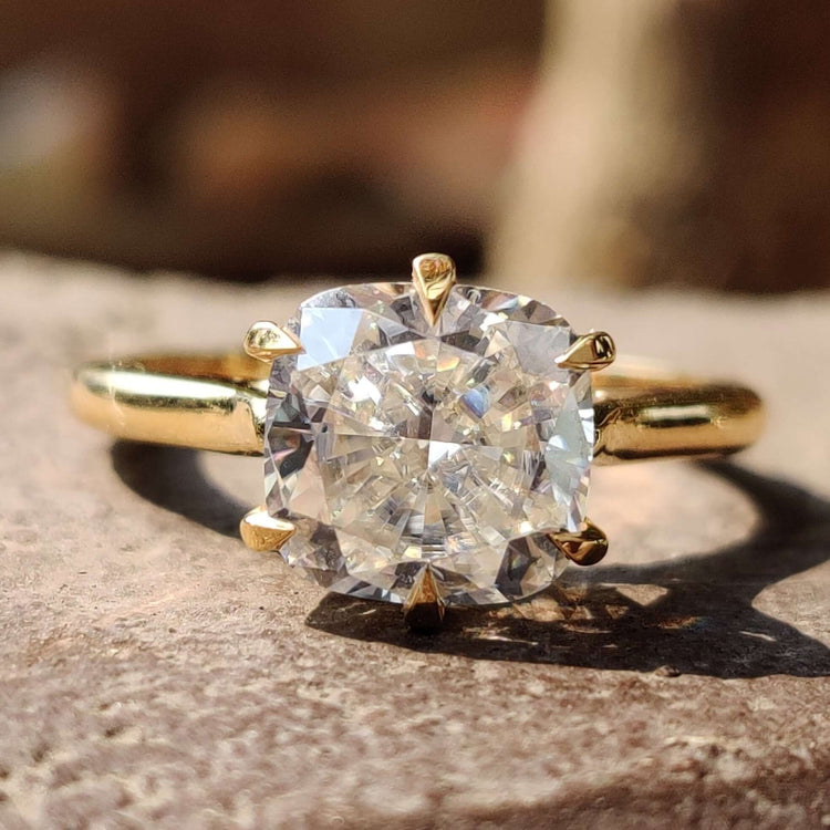 Cushion cut moissanite solitaire ring in yellow gold.
