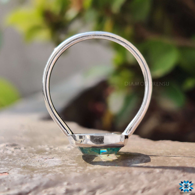 Simple bezel setting ring featuring a cushion cut cyan blue stone.
