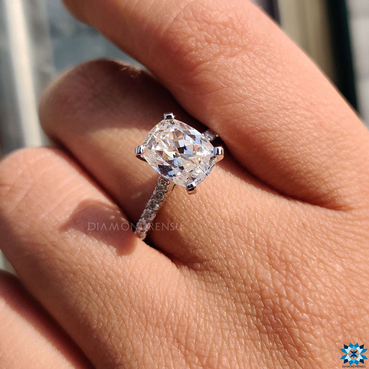 White gold engagement ring featuring a cushion cut center and 4 tab prongs.
