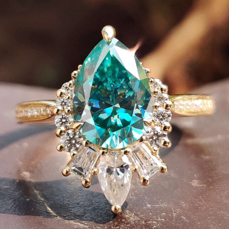 Pear shape engagement ring with green moissanite.
