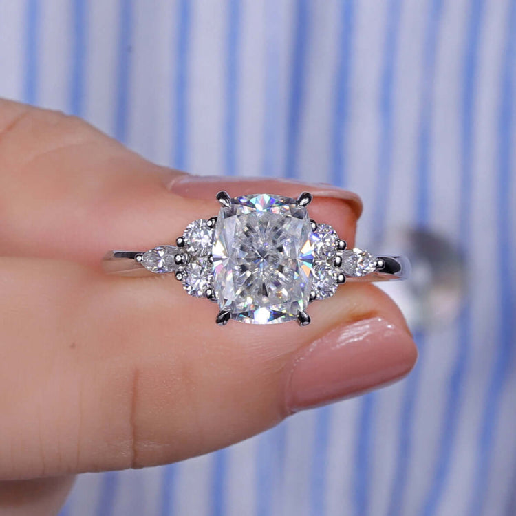 Cushion cut moissanite ring featuring marquise and round side stones.
