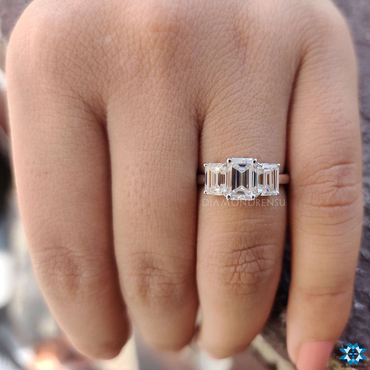Three stone moissanite ring with emerald cut center.
