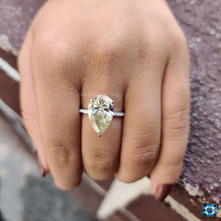 Pear shaped moissanite ring in white gold with hidden halo and pave accents.
