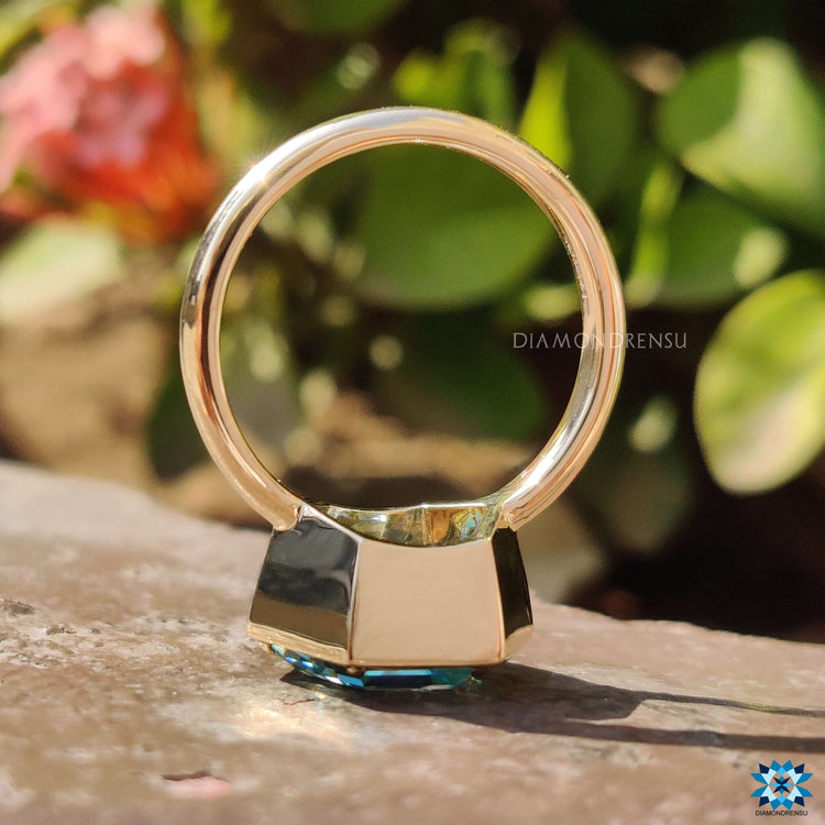 Bezel setting ring showcasing hexagon cut cyan blue moissanite in yellow gold.
