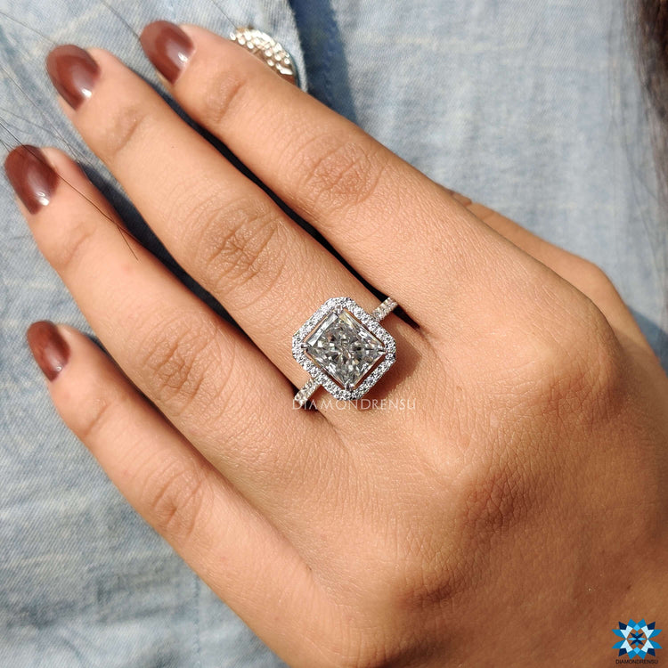 White gold moissanite ring with radiant cut center and round diamond accents.
