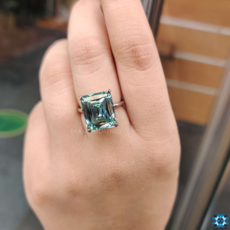 Custom engagement ring with cyan moissanite in 4 prong claw setting.
