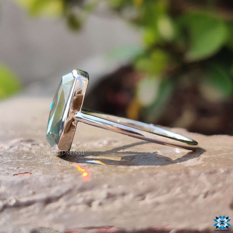 Solitaire moissanite ring with cyan blue cushion stone in white gold.
