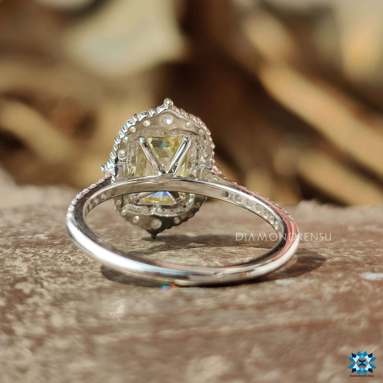 White gold ring featuring emerald cut moissanite and halo.
