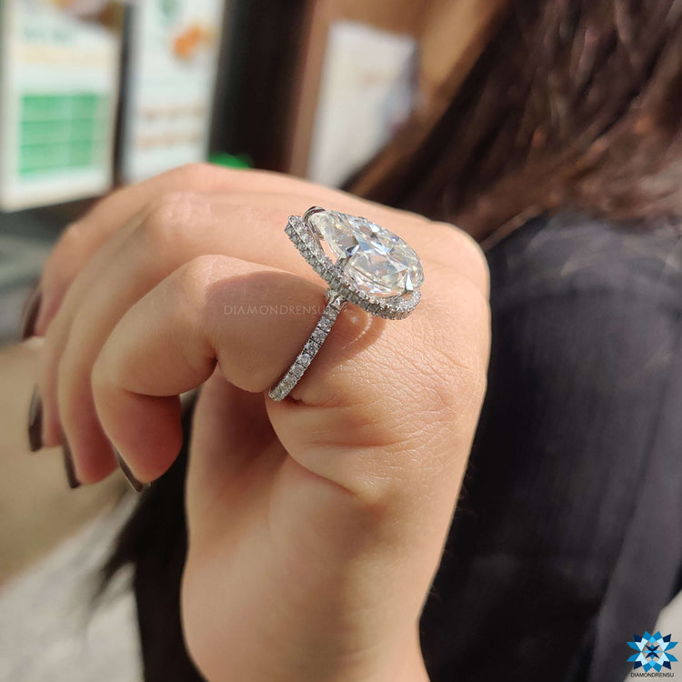 Old European cut engagement ring with pear silhouette and halo accents.
