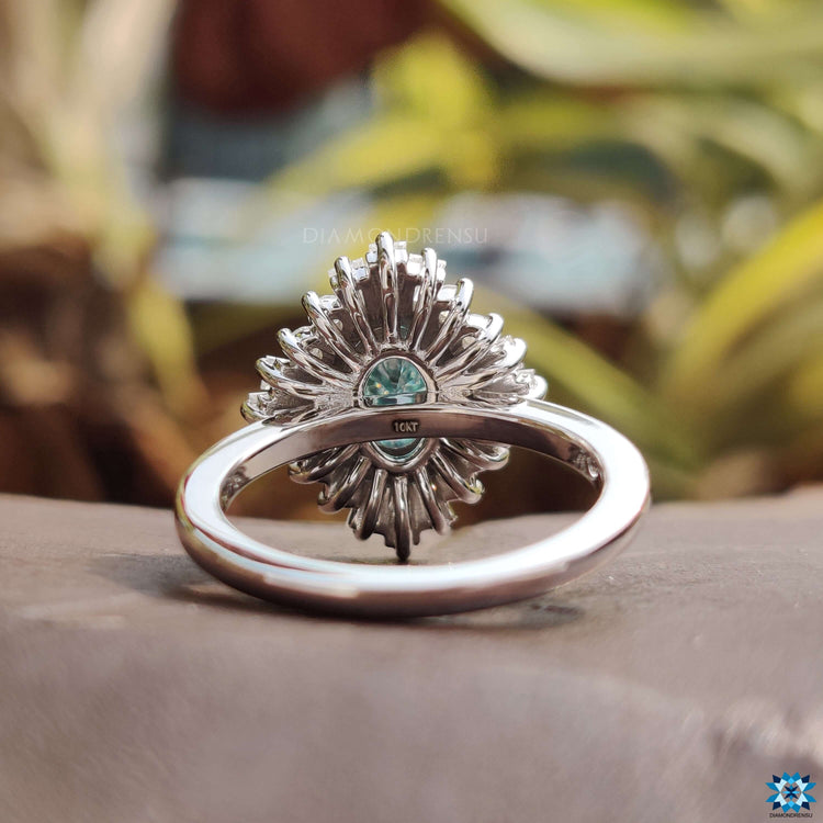 4 prong setting ring holding blue moissanite.
