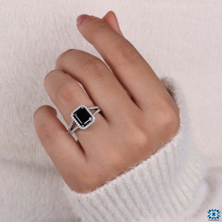 Split pave setting ring with round cut moissanite accents and emerald center.

