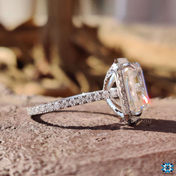Moissanite halo ring with emerald cut center and pavé band.
