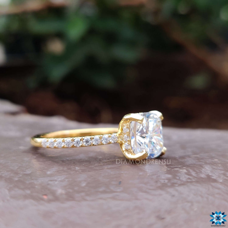 Moissanite pave ring featuring cushion cut stone and yellow gold finish.
