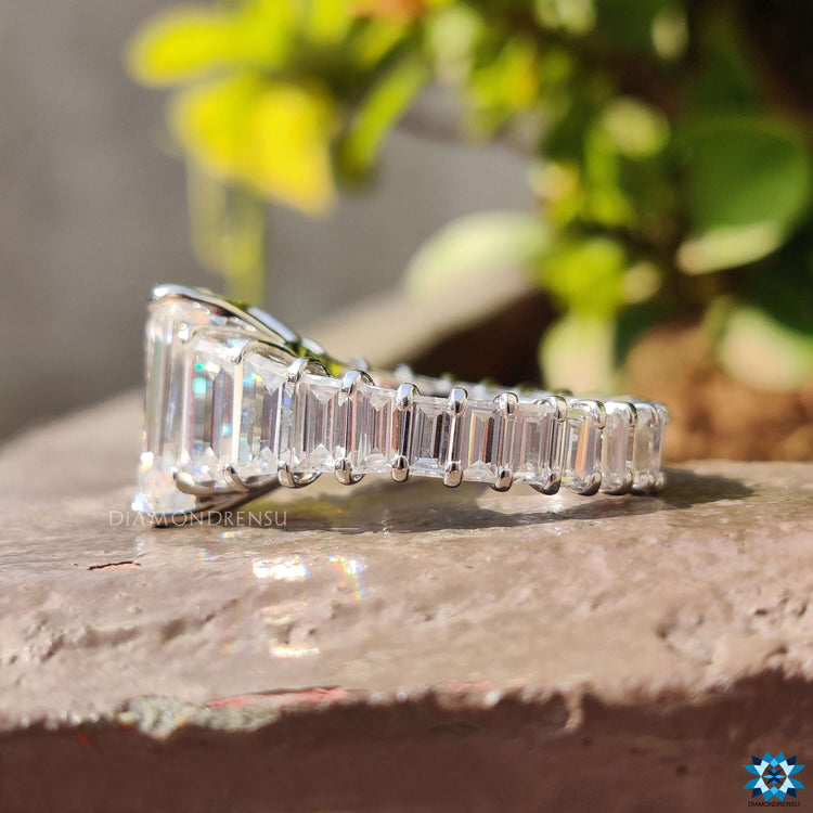 White gold ring with emerald cut moissanite and claw prong setting.

