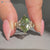 Green marquise diamond ring with round side stones.