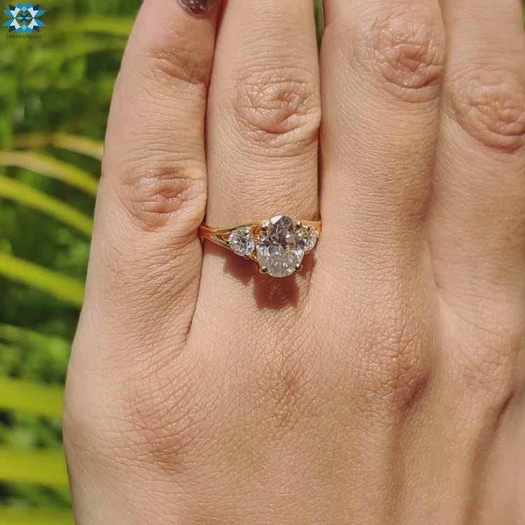 Gold engagement ring with oval center and side moissanites.
