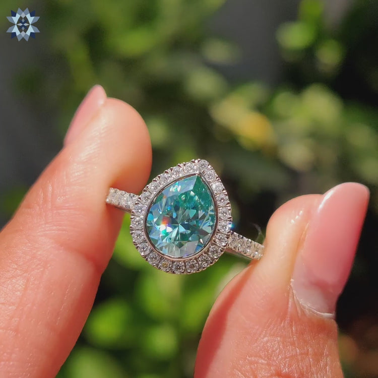 Moissanite pear ring featuring round cut pave band and bezel setting.
