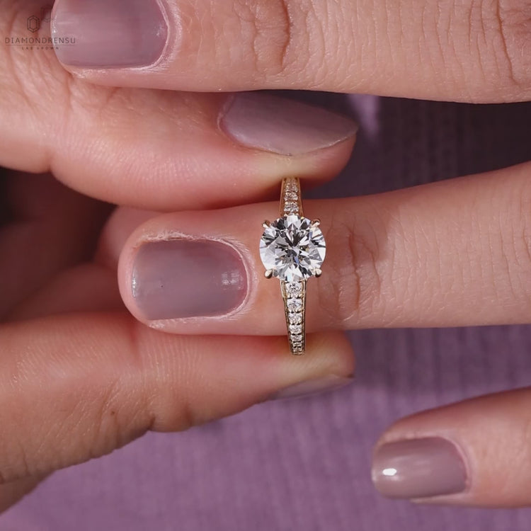 Round brilliant cut diamond engagement ring featuring handmade jewelry craftsmanship and a tapered band design.
