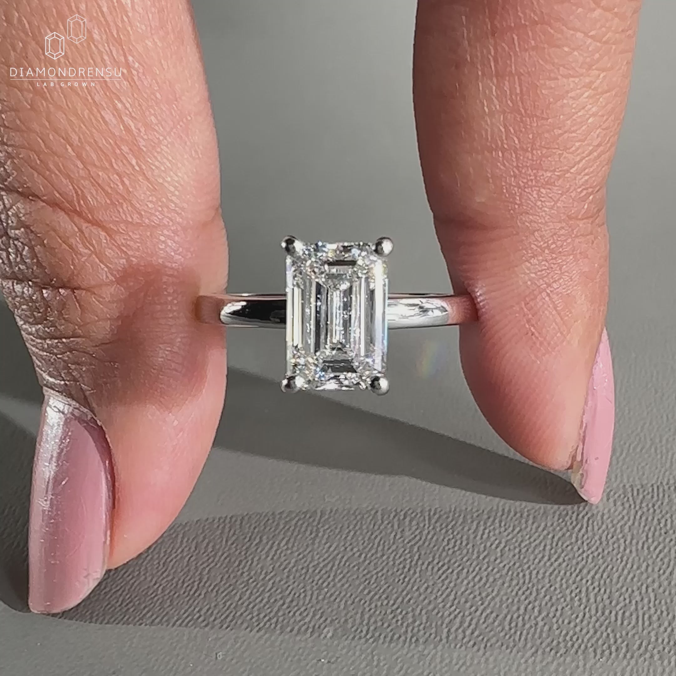 White gold emerald cut ring with an open gallery setting.
