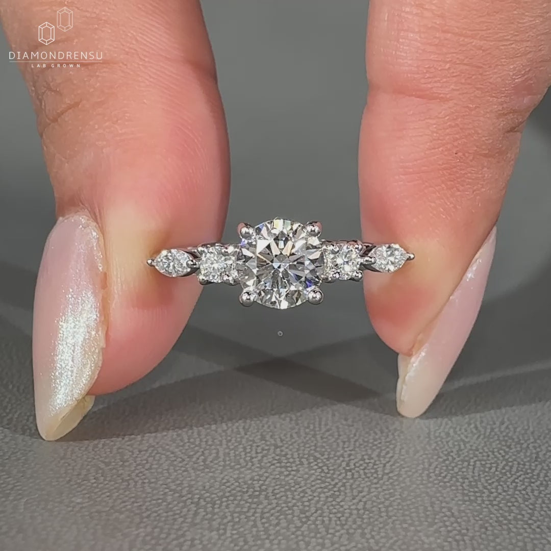 Round diamond engagement ring with marquise side stones.
