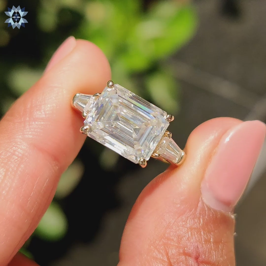 Three stone moissanite ring with yellow gold band and side stones.
