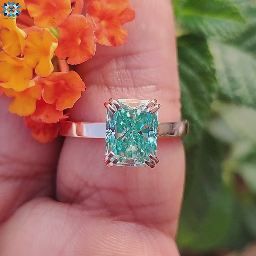 Cyan blue moissanite ring with a radiant cut stone set in a luxurious band for a unique, colorful style.
