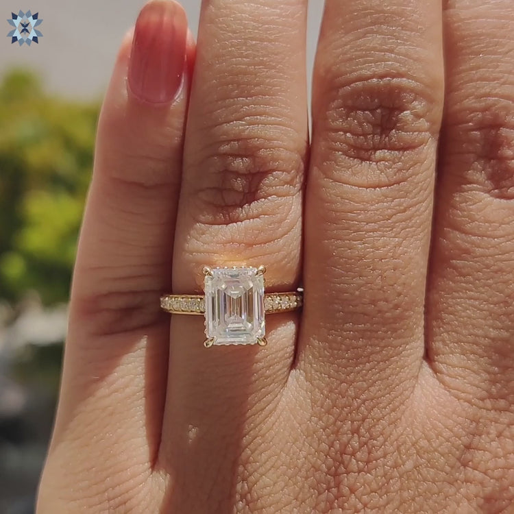 Classic emerald cut moissanite ring in cathedral setting with round pave.
