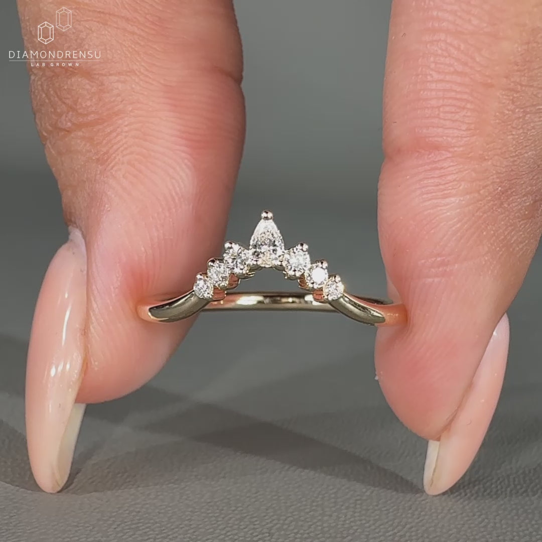 Pear and round diamond band in a curved yellow gold design.
