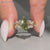 Green marquise diamond ring with round side stones.