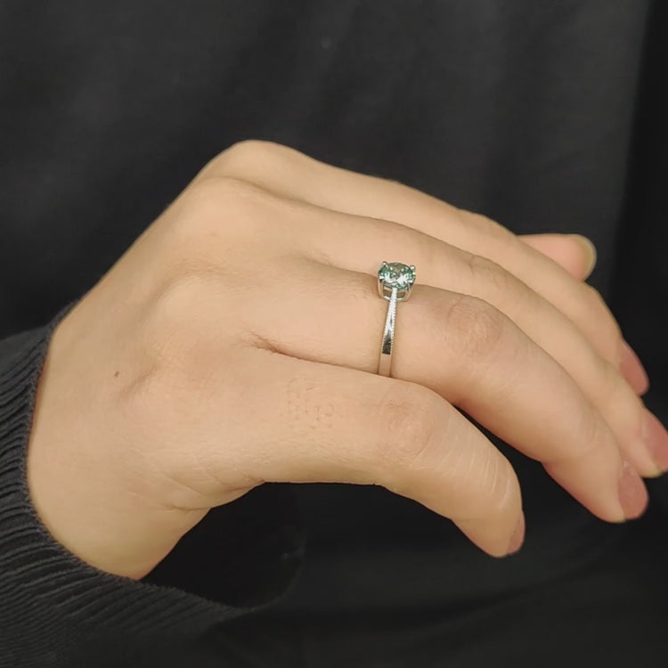 Solitaire engagement ring with cyan blue moissanite.
