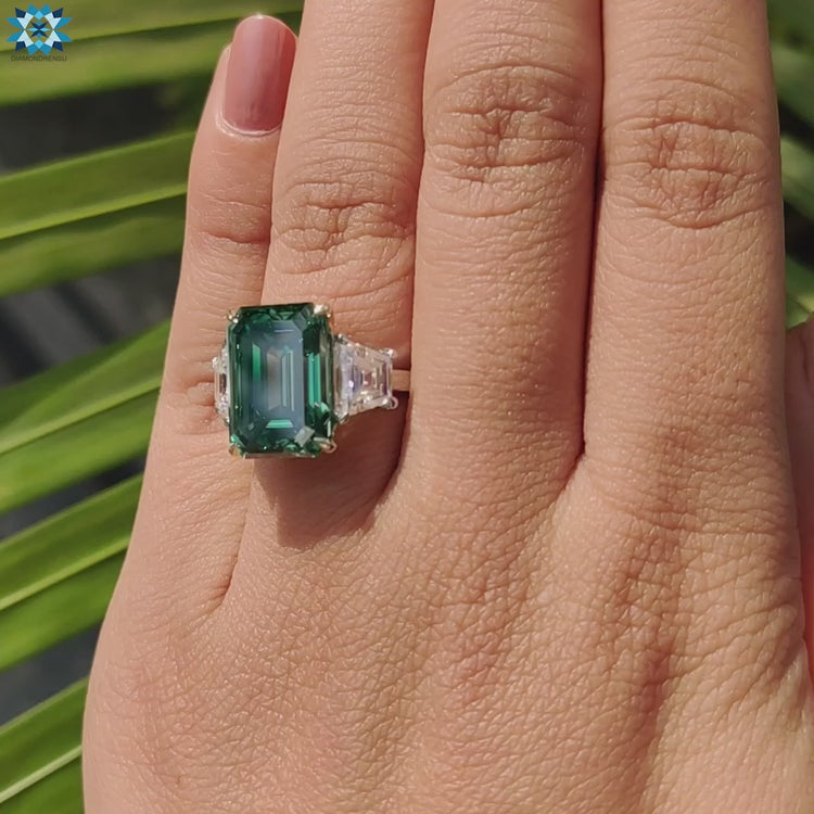 Three stone ring with prong setting and green moissanite.
