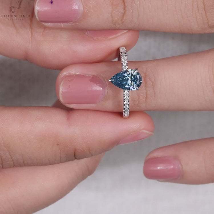 Blue diamond pear shaped ring with pave diamond accents, perfect for engagement ring seekers.
