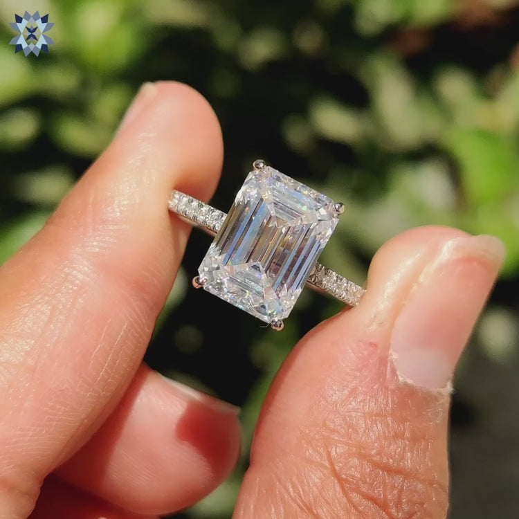 Hidden halo ring featuring emerald cut moissanite and round cut pave detail.
