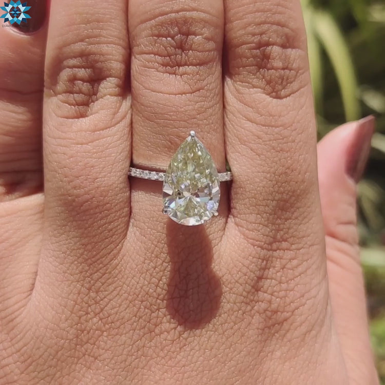 Moissanite engagement ring with pear shaped light yellow center stone.
