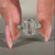 White gold engagement ring with green emerald side stones and prong setting.
